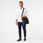 Chris Louis black leather messenger bag with multiple compartments and buckle closure, worn by a woman.