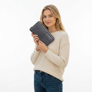 Chris Louis black leather zip around wallet organizer with white stitching and snap pocket. Model holds wallet.