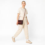 Chris Louis brown leather crossbody wallet with orange strap and trim, featuring a flap closure and embossed logo.