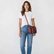 Chris Louis brown genuine leather satchel handbag with orange accents on handles and strap. Features a spacious compartment and adjustable strap.