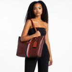 Chris Louis brown leather tote bag with orange straps and vertical orange, white, and grey stripe accent.