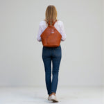 Chris Louis Jarrah tan leather hexagon backpack with adjustable straps and front zipper pocket.
