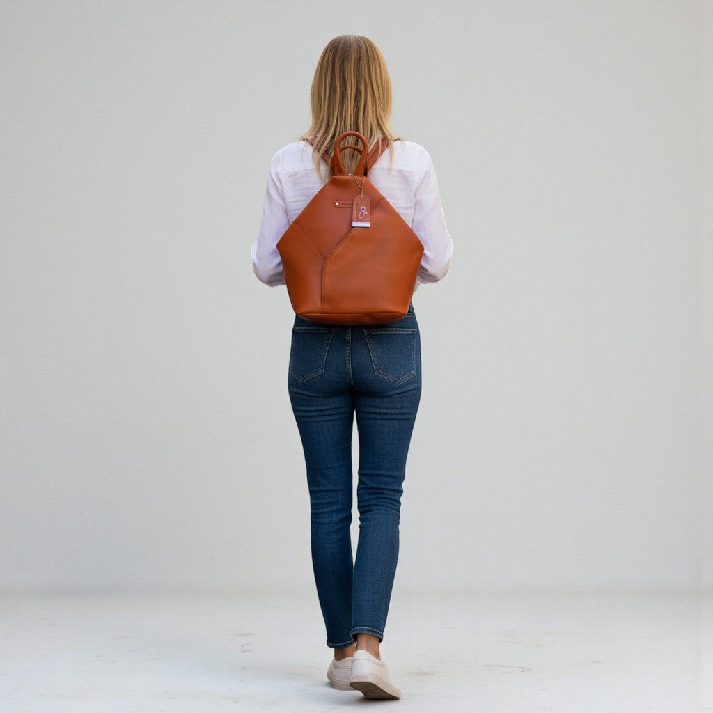 Chris Louis Jarrah tan leather hexagon backpack with adjustable straps and front zipper pocket.