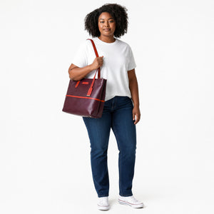 Chris Louis brown leather tote bag with orange straps and trim. Features a zip top closure and a hanging luggage tag.