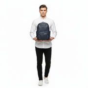 Chris Louis navy blue leather unisex backpack with adjustable padded straps and exterior pockets, carried by a woman.
