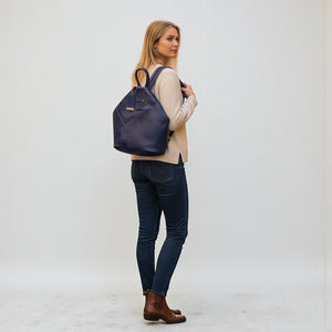 Chris Louis navy blue genuine leather hexagon shoulder bag with adjustable straps, worn by a woman on a cobblestone street.