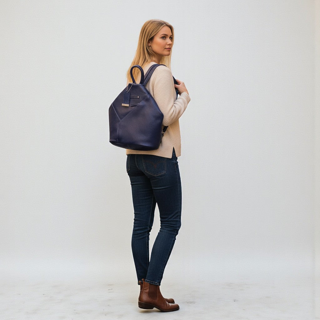 Chris Louis navy blue genuine leather hexagon shoulder bag with adjustable straps, worn by a woman on a cobblestone street.