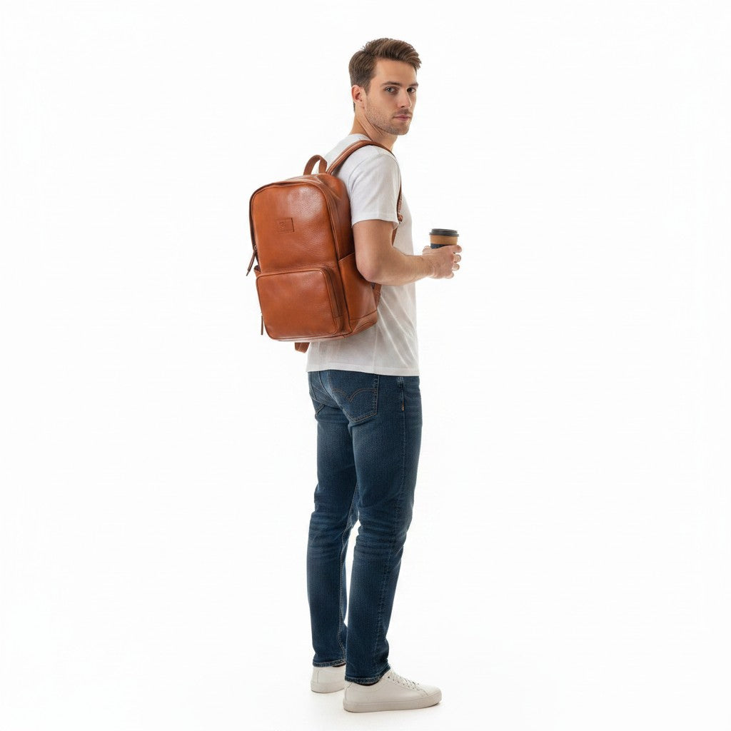Chris Louis tan leather unisex backpack with front pocket, worn by a woman holding a coffee cup.