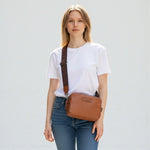 Chris Louis Moolicious sling bag in tan full grain leather with signature webbed strap, worn by a woman.