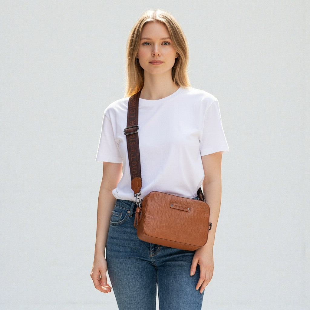Chris Louis Moolicious sling bag in tan full grain leather with signature webbed strap, worn by a woman.
